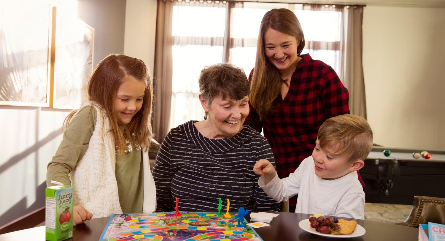 A resident enjoys a cheerful board game with visiting family, capturing the warm, multigenerational moments at senior living near Carrollwood, FL.