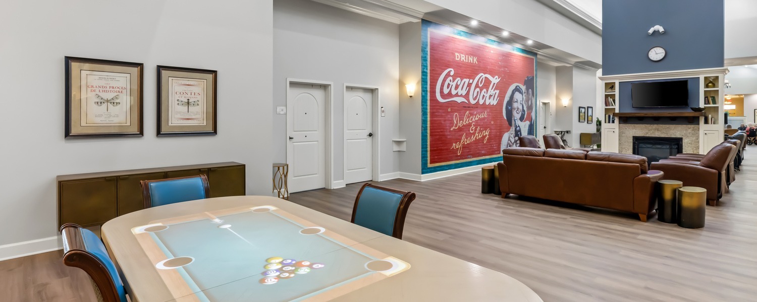 Game room with a card table and cozy lounge featuring a fireplace and TV, part of the resort-style senior amenities at our senior living community in Acworth, GA