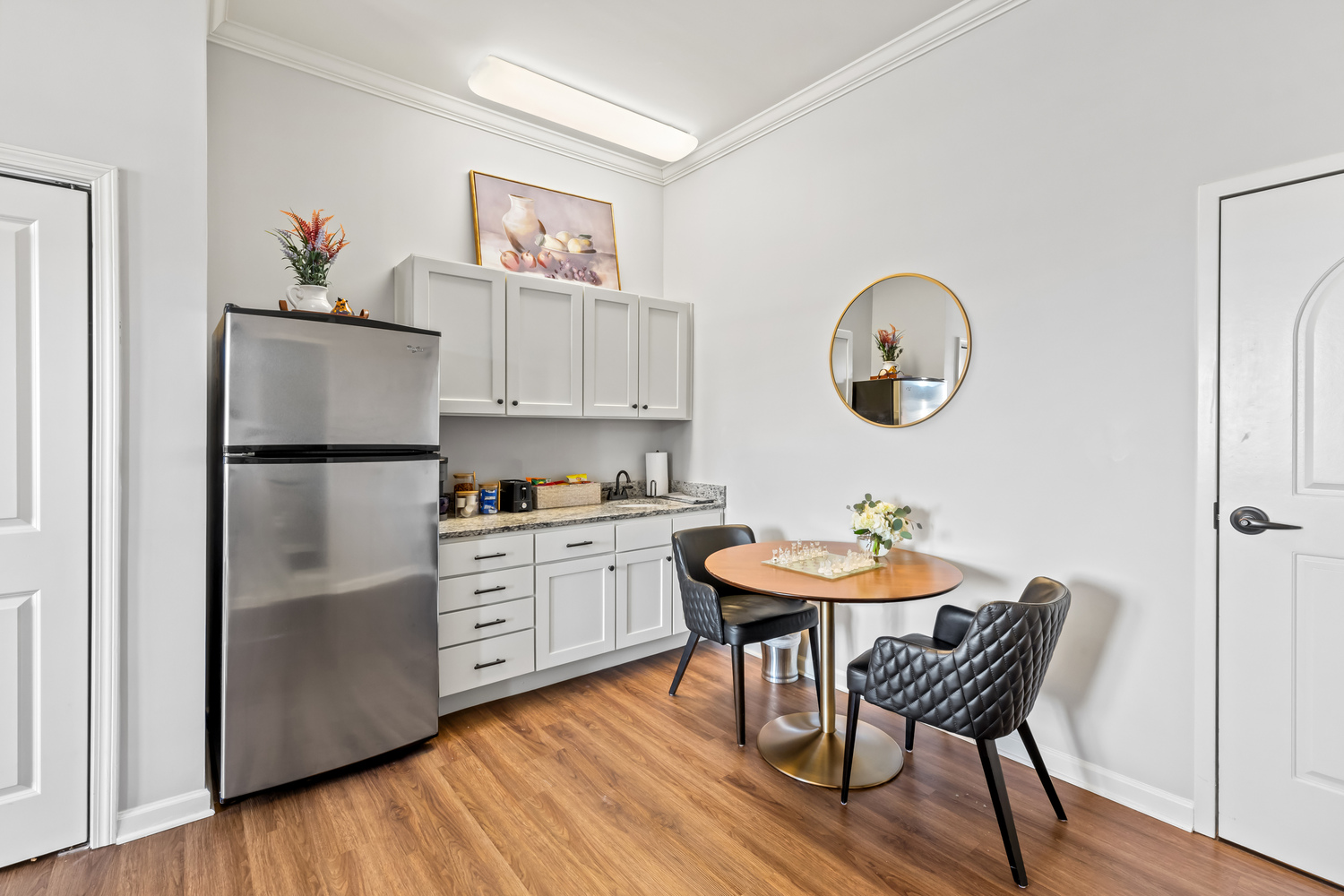 A compact and functional kitchenette in a model apartment at this assisted living community in Acworth, GA, featuring stainless steel appliances, white cabinetry, and a small dining nook.