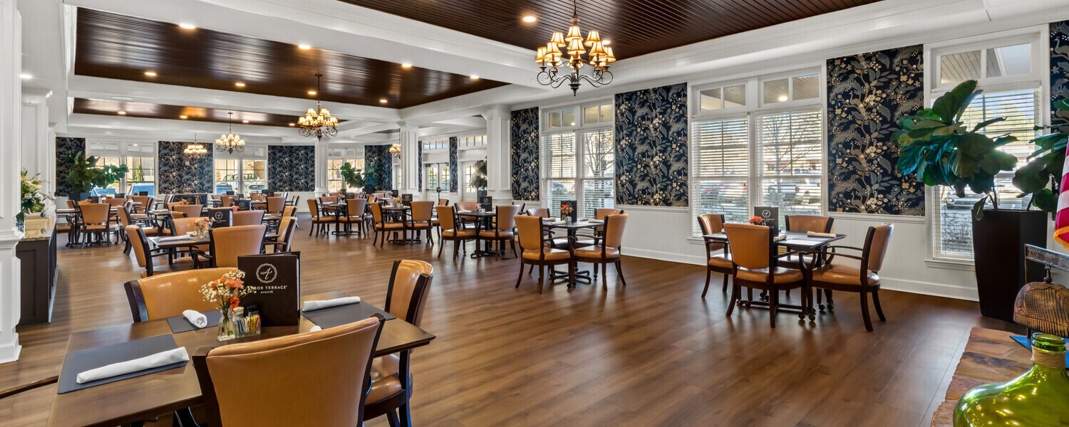 A spacious dining and living area at this senior living community in Acworth, GA, featuring warm wood floors, chandelier lighting, and charming decor that makes residents feel right at home.