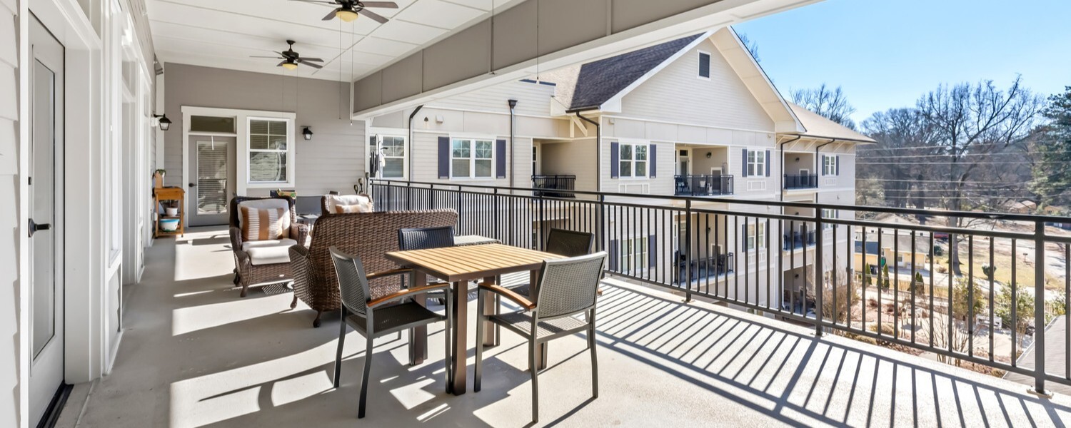 A sun-filled outdoor patio at this Acworth senior living community, featuring a ceiling fan, café-style seating, and views of the surrounding landscape, perfect for relaxing and enjoying fresh air.