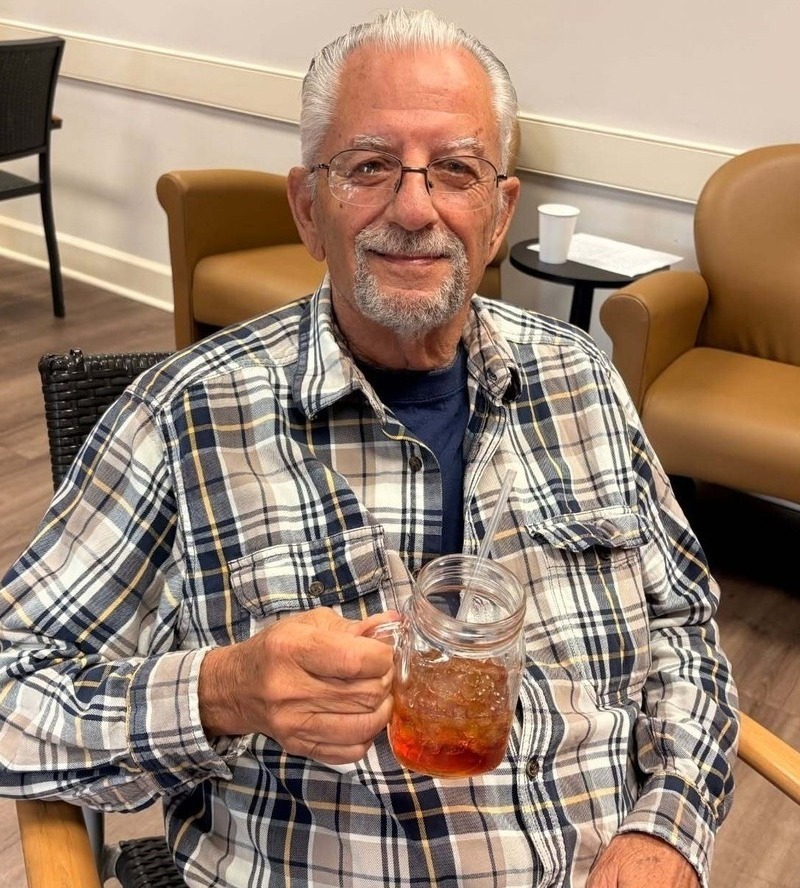 Resident smiling while enjoying a refreshing drink in a cozy lounge setting at our senior living community in Acworth, GA, part of our engaging senior lifestyle programs
