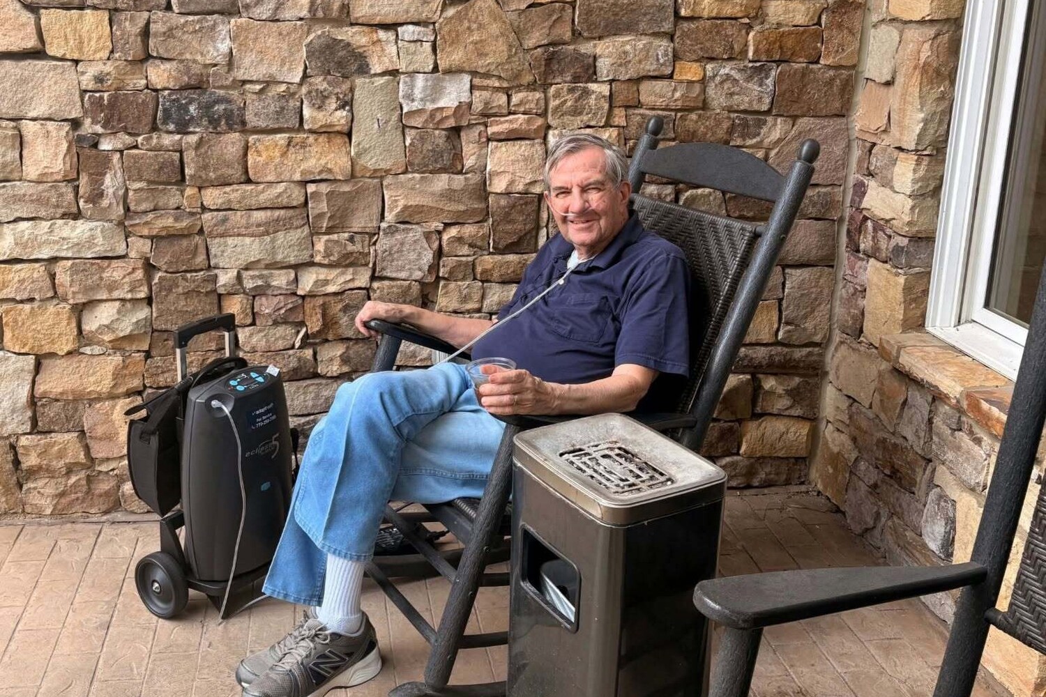 Resident relaxing on a shaded patio with stone wall accents, part of the resort-style senior amenities at our senior living community in Acworth, GA