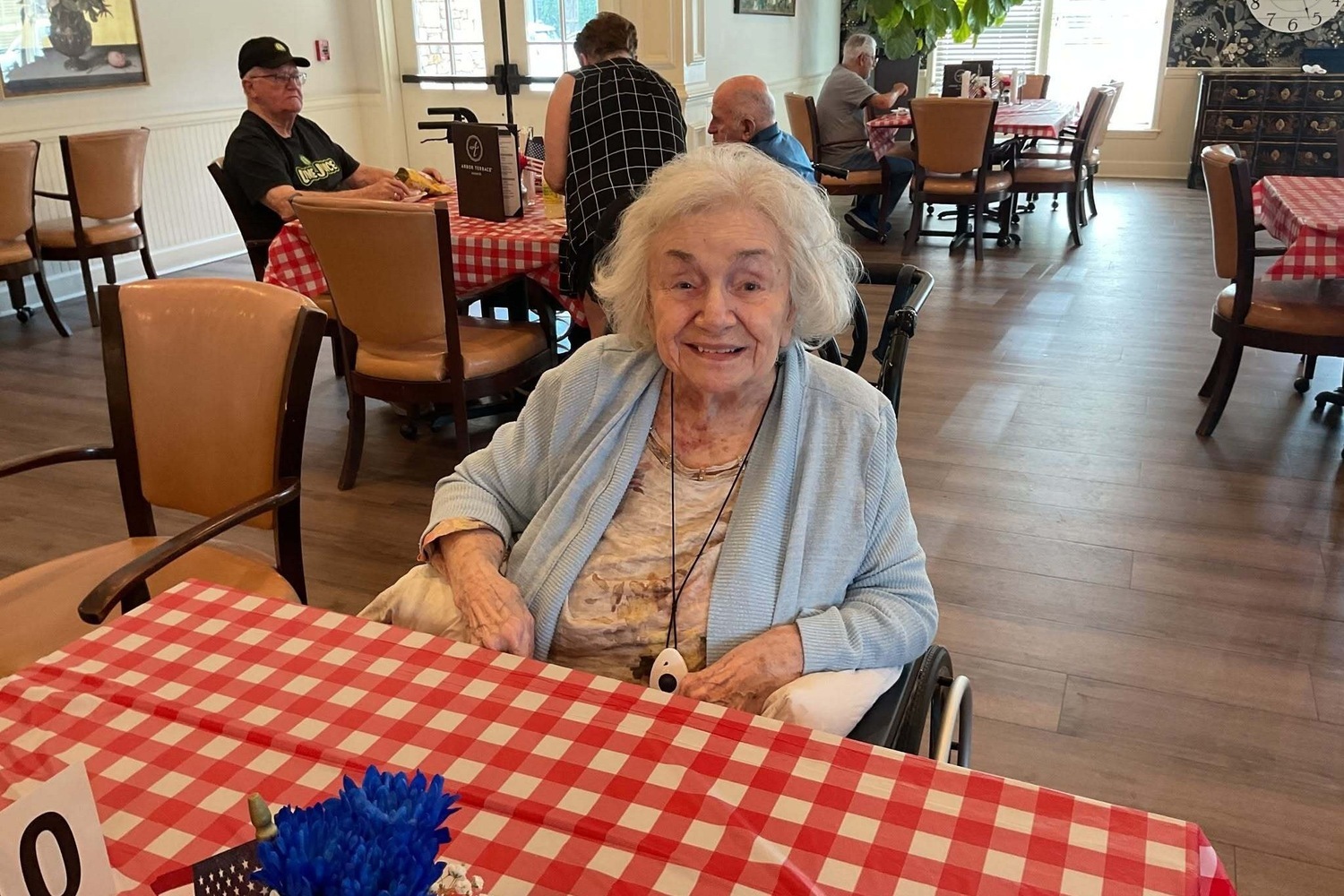 Resident smiling at a table set with a cheerful checkered tablecloth at our senior living community in Acworth, GA, enjoying our engaging senior lifestyle programs