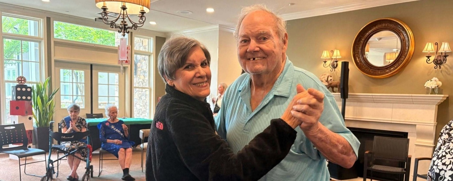 Two residents sharing a dance in a bright common area at our senior living community in Acworth, GA, part of our engaging senior lifestyle programs
