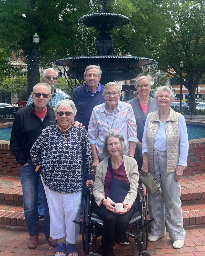 Residents posing together near a fountain during a group outing, reflecting the active senior lifestyle at our senior living community in Acworth, GA
