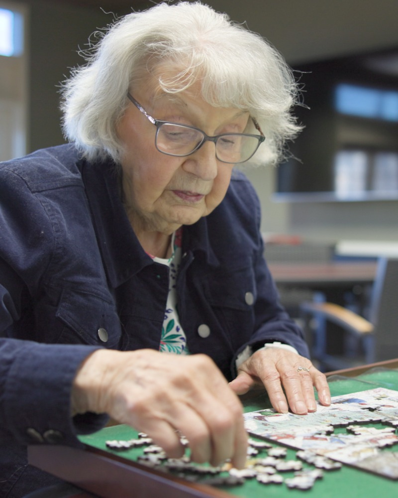 Resident focused on completing a jigsaw puzzle at our senior living community in Acworth, GA, part of our engaging senior lifestyle programs