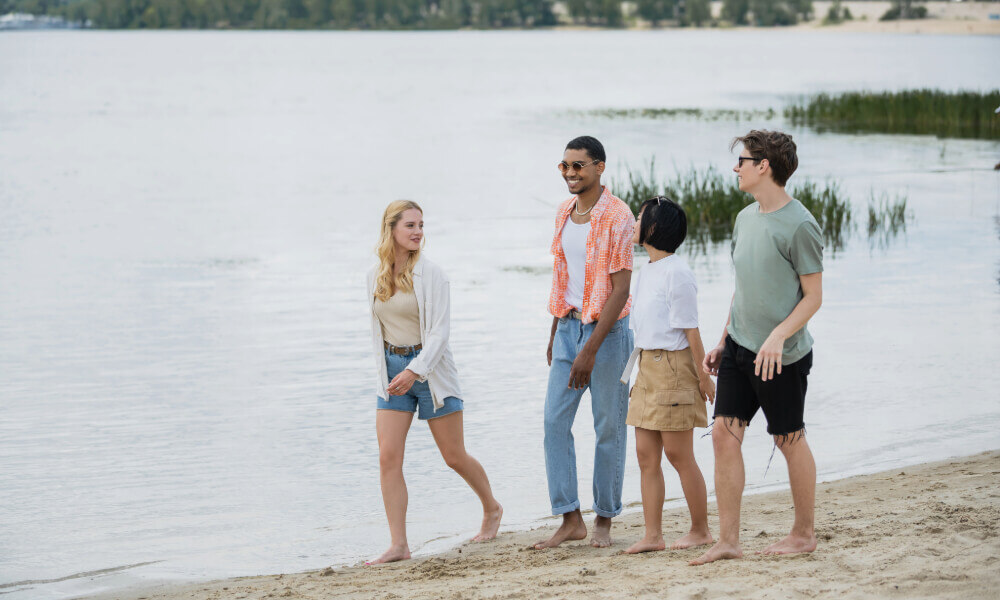 A group of people enjoy a sunny day along the sandy shoreline near Acworth, GA, with calm lake waters stretching into the background, reflecting the scenic outdoor lifestyle near this senior living community.