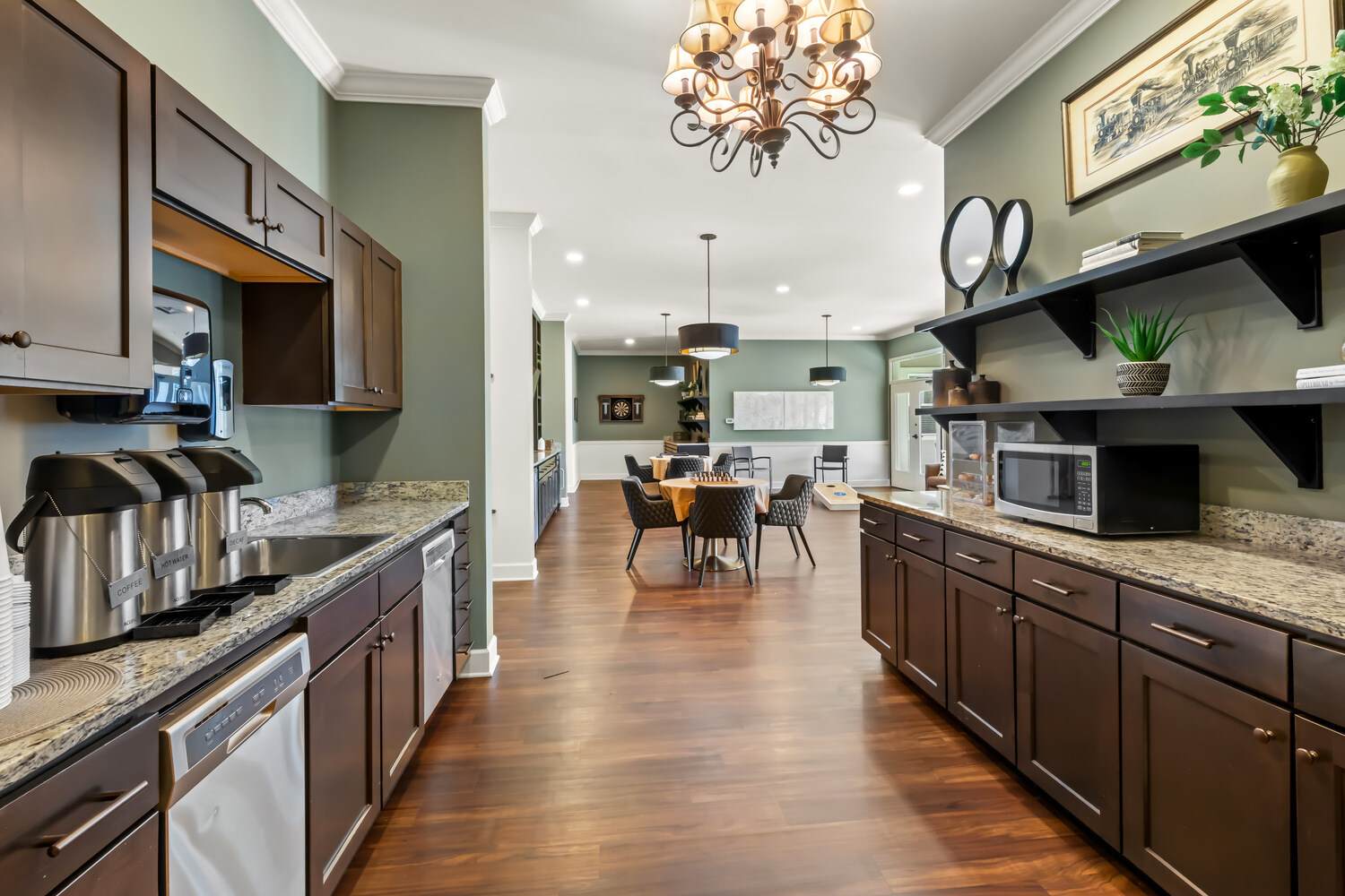 A fully equipped residential kitchen at this Acworth senior living community, featuring dark wood cabinetry, granite countertops, stainless steel appliances, and an open flow into the dining area.