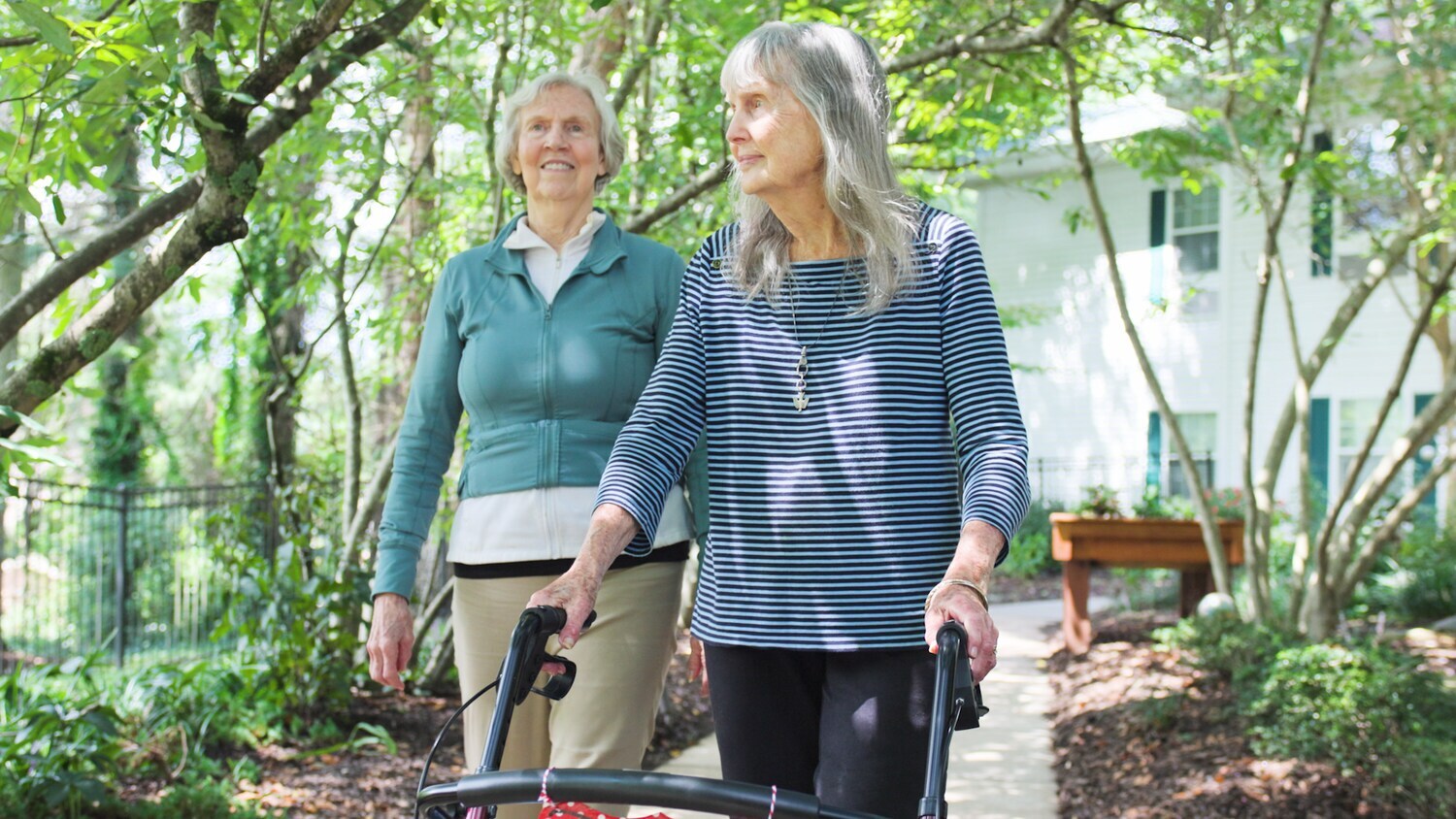 Two people walk side by side along a lush, tree-lined path, enjoying the fresh outdoors at this welcoming senior living community in Asheville, NC.