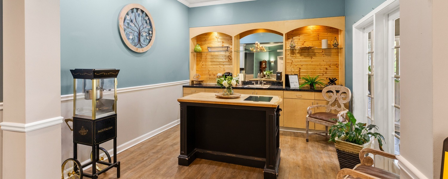 A cozy amenity nook with wood cabinetry, a round wall clock, and a popcorn cart at Arbor Terrace Athens, a senior living community in Athens, GA, reflecting resort-style senior living in Athens, GA.