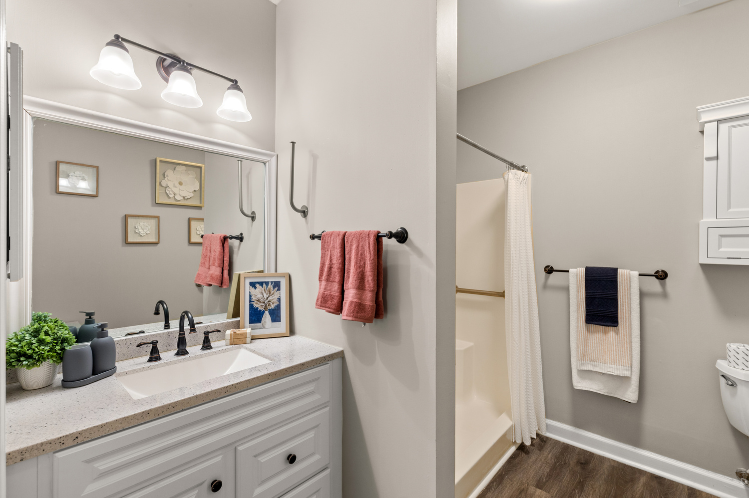 A clean, well-appointed model bathroom at Arbor Terrace Athens featuring double sinks, warm wood cabinetry, and bright lighting, reflecting the thoughtful design of this senior living community in Athens, GA.