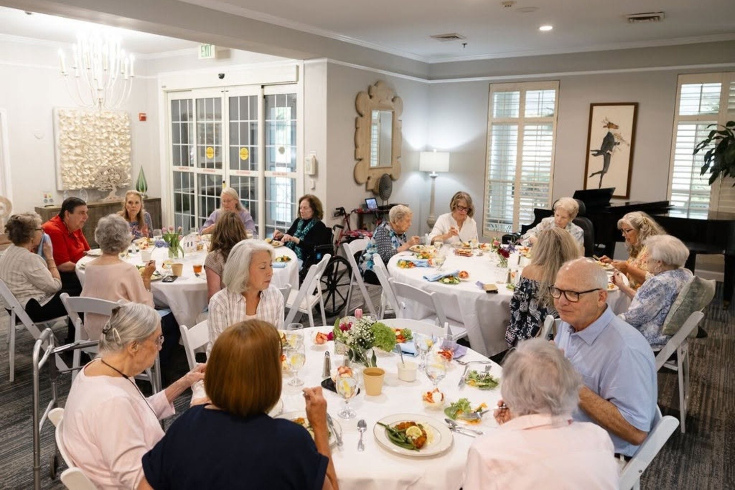 Residents and guests gather at round tables for a lively group dining event at Arbor Terrace Athens, a senior living community in Athens, GA, showcasing resort-style senior living in Athens, GA.