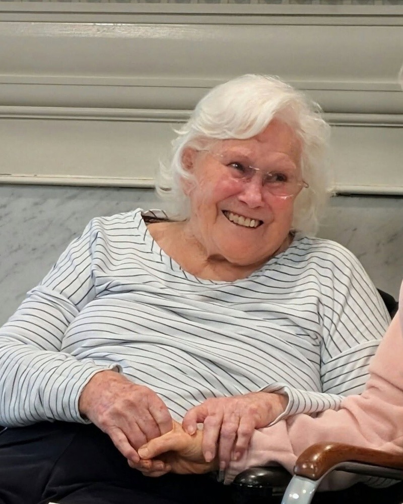 A resident smiles warmly while seated in a cozy common area at Arbor Terrace Athens, reflecting the friendly and welcoming spirit of senior living in Athens, GA.