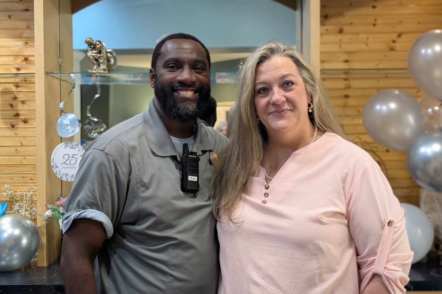 Two smiling staff members pose together at a milestone celebration with silver balloon decor at Arbor Terrace Athens, a senior living community in Athens, GA, part of active senior living in Athens, GA.