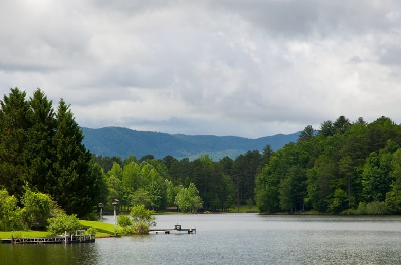 Rolling green hills and a distant lake beneath a cloudy sky near Watkinsville, GA, close to Arbor Terrace Athens, which offers senior living in Watkinsville, GA and senior living near Oconee County, GA.