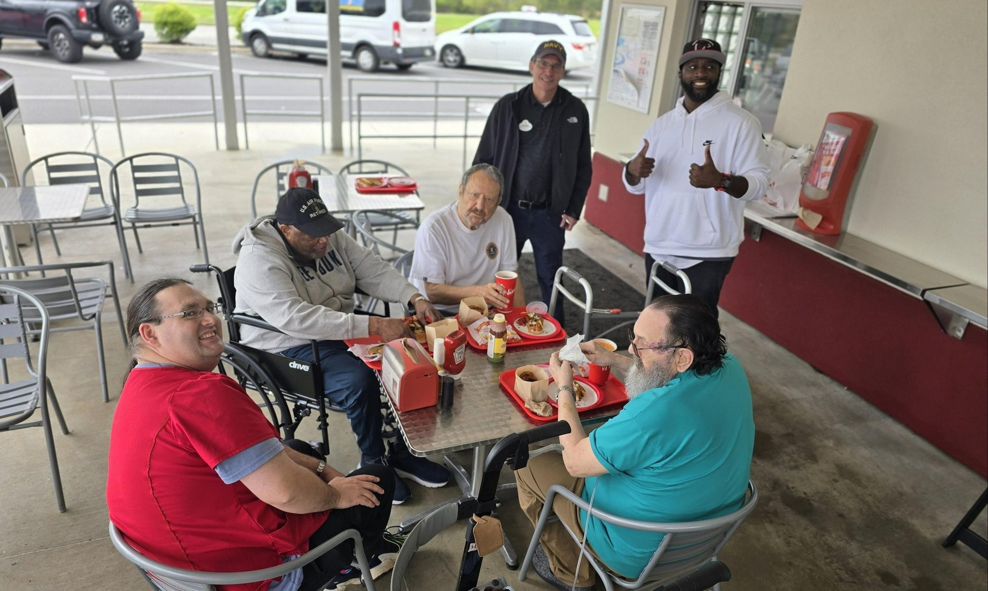 A group of residents and staff enjoying a meal together at a local restaurant during a Men's Club outing from Arbor Terrace Athens, highlighting the active lifestyle and social engagement at this senior living community in Athens, GA.