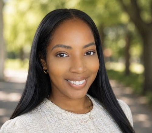 A smiling staff member at Arbor Terrace Athens, a senior living community in Athens, GA, photographed outdoors with a soft, tree-lined background.