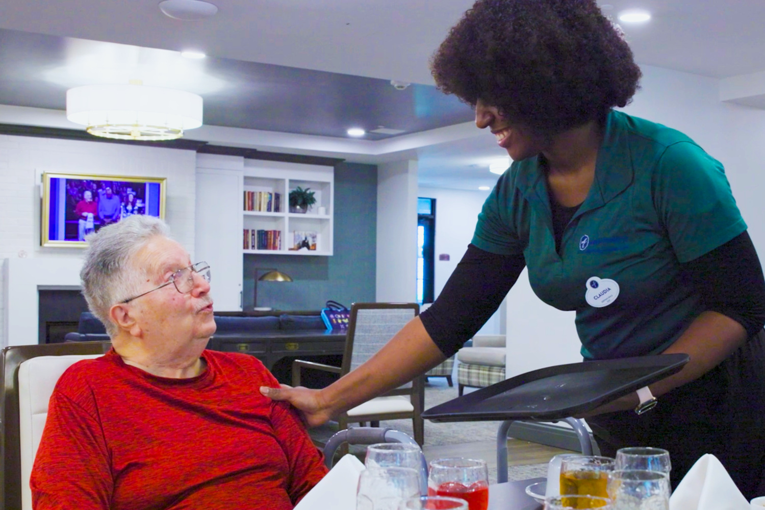 A woman in a gray tank top leads a seated exercise class in a spacious room with wood floors and large windows as participants follow her moves, highlighting resort-style senior living Basking Ridge, NJ, and senior living near Mendham, NJ.