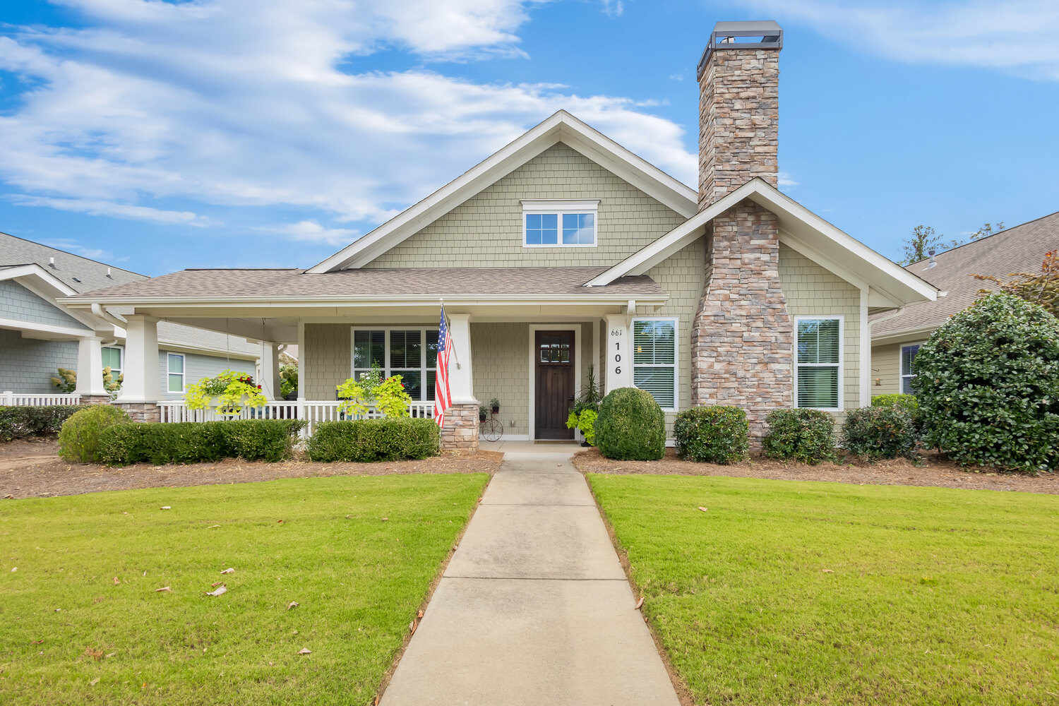 A charming cottage-style home with a stone chimney, manicured lawn, and welcoming front walkway at The Arbor at BridgeMill senior living community in Canton, GA.