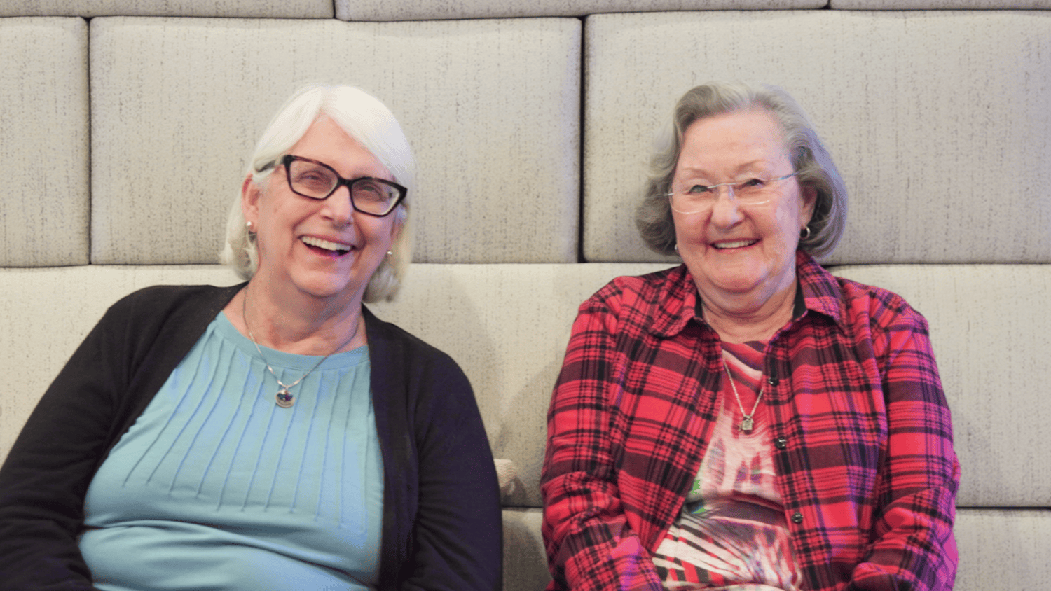 Two senior residents smiling and sitting