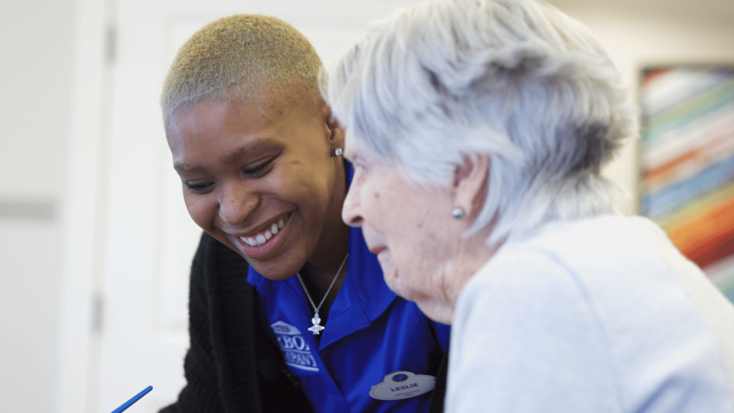 A staff member shares a warm laugh with a resident at Arbor Terrace Burnt Hickory, capturing the genuine connections and caring atmosphere at this senior living community in Marietta, GA.