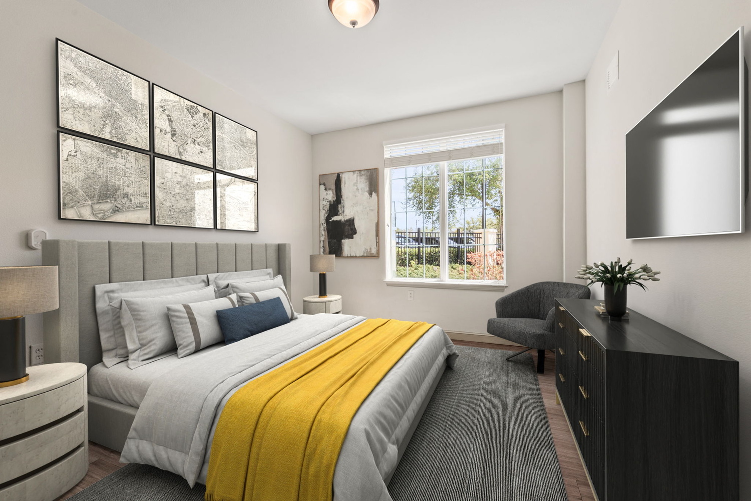 A well-appointed apartment bedroom at Arbor Terrace Citrus Park, featuring a tall upholstered headboard, yellow accent bedding, a gallery wall of map prints, and a wall-mounted TV, part of senior living in Tampa, FL.