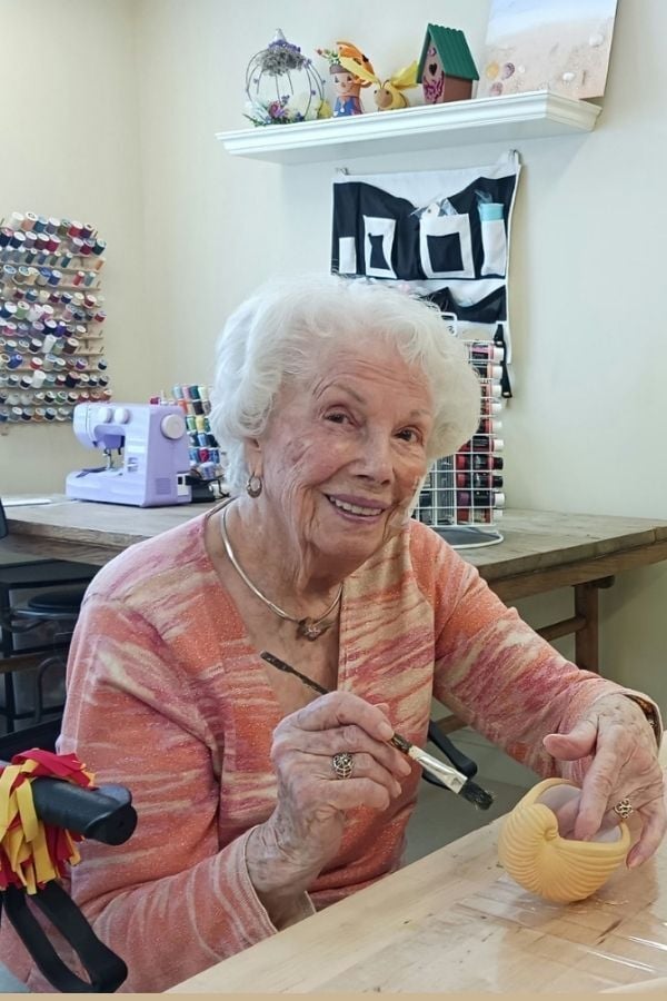 Senior lady painting a shell in the art room