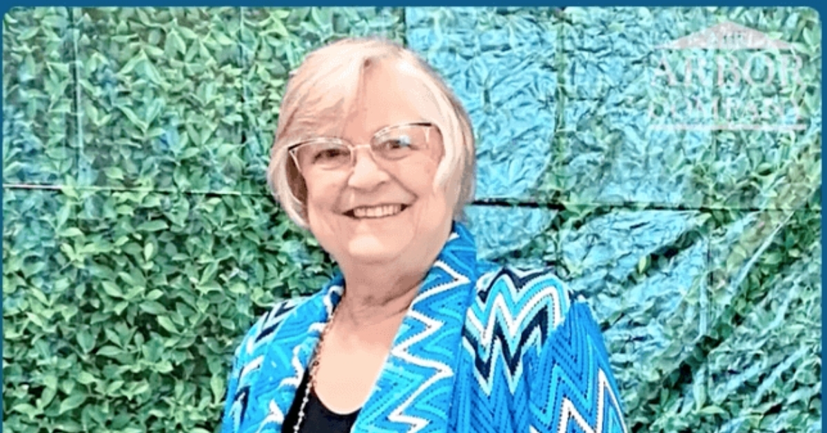 A smiling resident poses against a lush green wall backdrop, capturing a joyful moment at senior living near Carrollwood, FL.