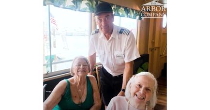 Two residents smile alongside a boat captain during a waterfront outing, capturing the vibrant, active senior living near the Tampa Bay waterfront.