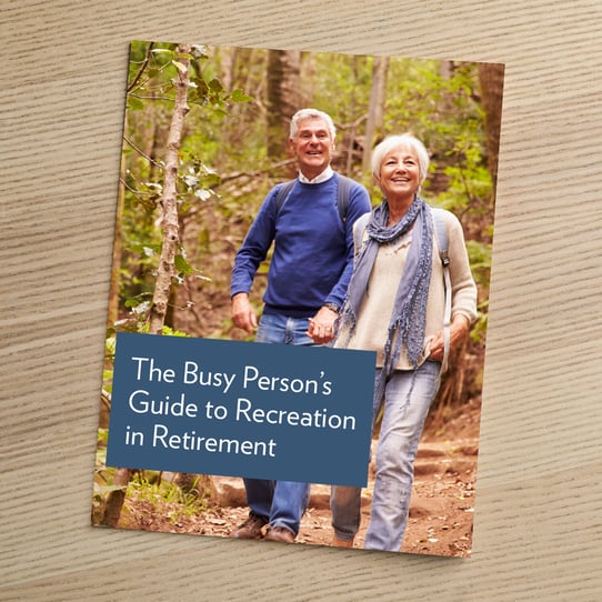 Cover of a brochure titled "The Busy Person's Guide to Recreation in Retirement," featuring a happy older couple walking hand-in-hand on a wooded trail.