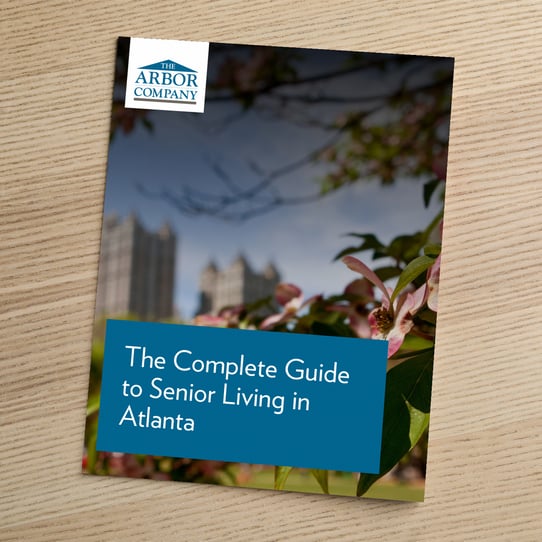 The Arbor Company cover for 'The Complete Guide to Senior Living in Atlanta,' showing flowering tree branches with the Atlanta skyline in the background.