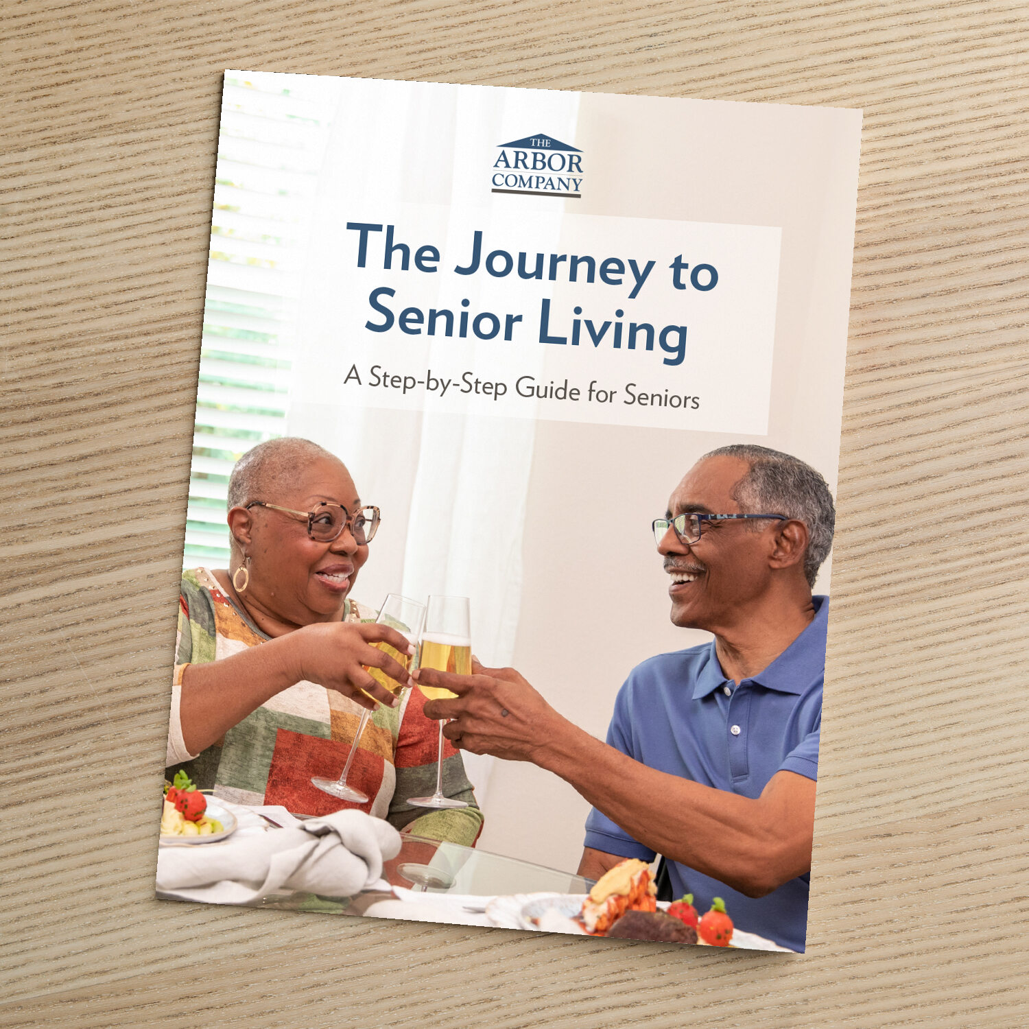 Cover of The Arbor Company guide titled "The Journey to Senior Living: A Step-by-Step Guide for Seniors," featuring an older couple toasting with wine glasses over a meal.
