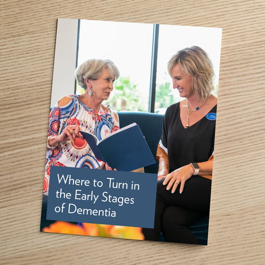 Cover of a brochure titled "Where to Turn in the Early Stages of Dementia," showing two women seated together reviewing a blue folder.