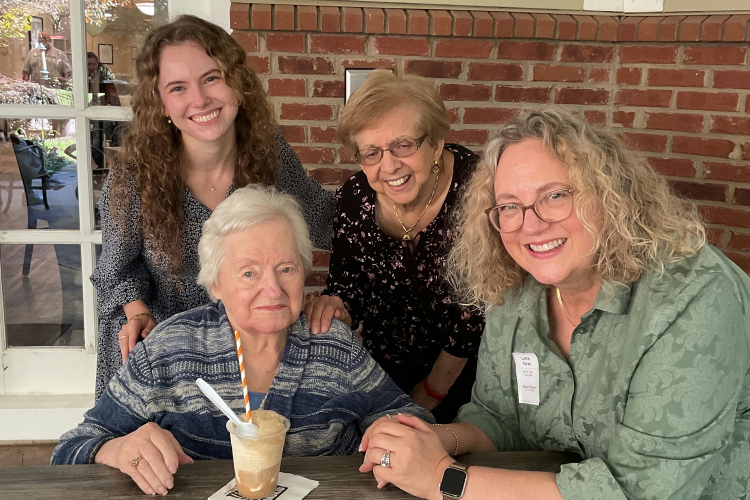 A resident poses with family members over drinks, capturing warm connections central to senior living in Alpharetta, GA and senior living with social activities in Alpharetta, GA.
