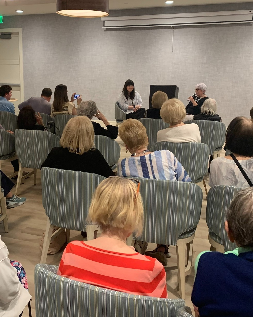 Residents and guests fill a modern event space at The Arbor at Delray for a community presentation, highlighting the enriching programming and social engagement offered at this senior living community in Delray Beach, FL.