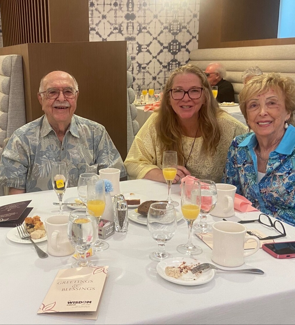 Residents and a guest share mimosas and a meal in the warmly decorated dining room at The Arbor at Delray, reflecting the inviting social atmosphere of senior living in Delray Beach, FL.
