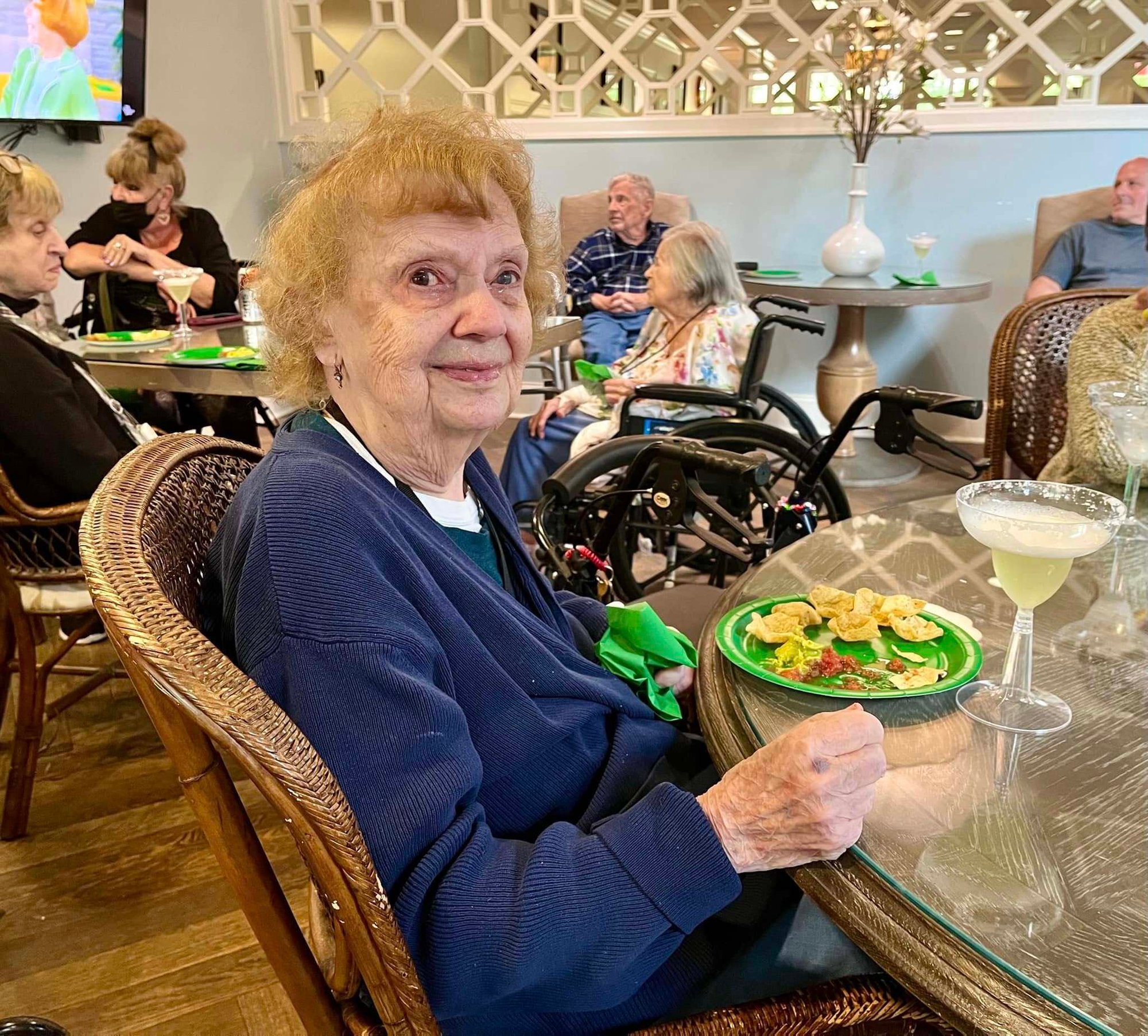 A resident enjoys a fresh salad and a cocktail at a beautifully set table in the dining room at this senior living community in Warrington, PA.