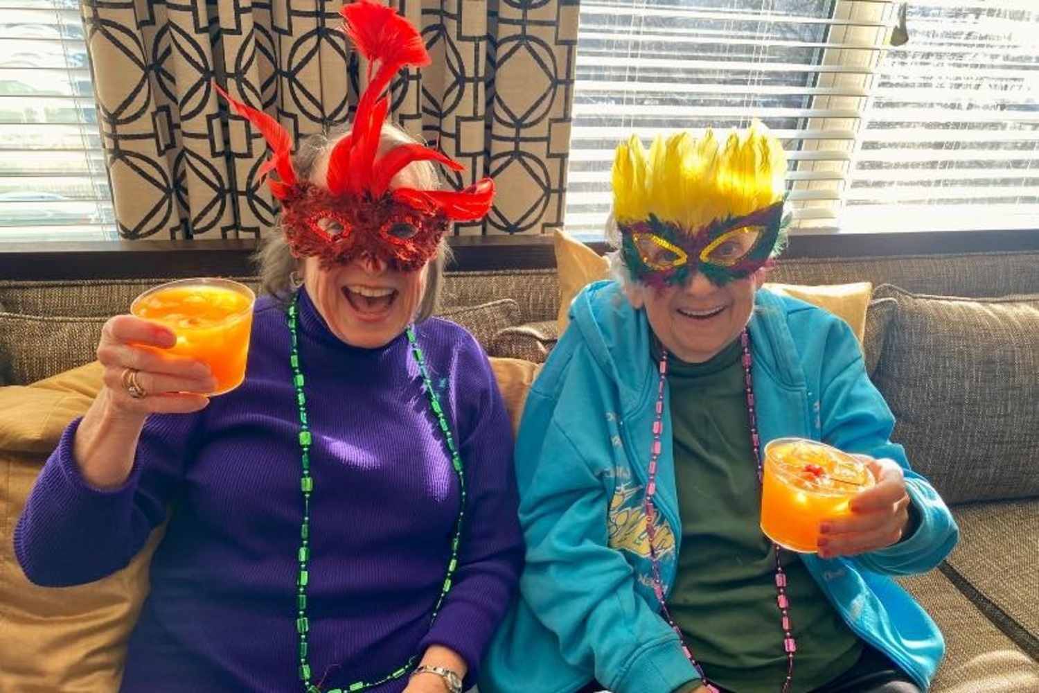 two senior residents wearing creative masks while enjoying drinks
