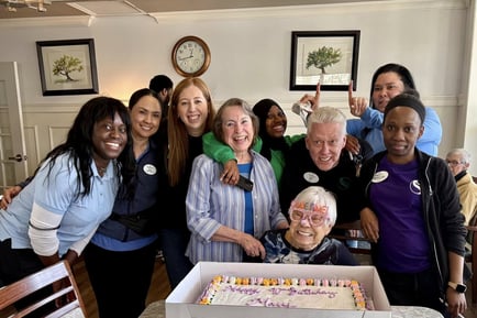 Staff members and friends gathered together for a picture celebrating a residents birthday in the common area 