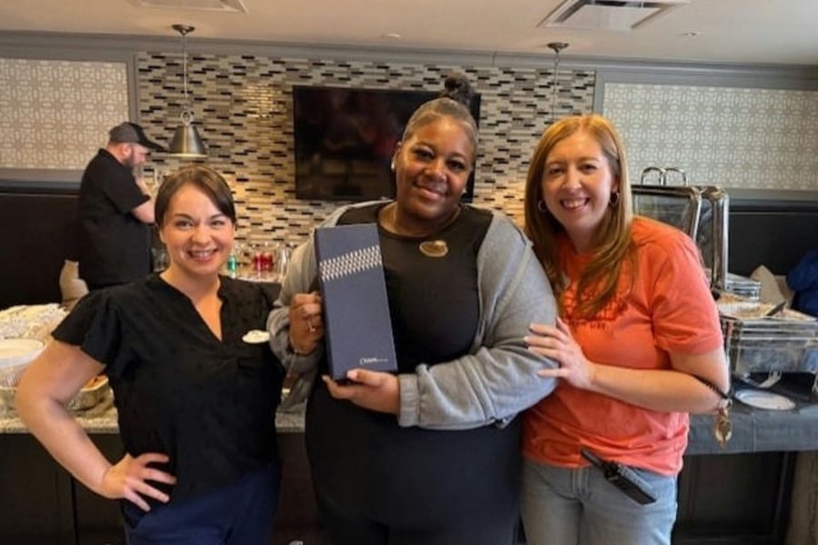 Doylestown staff members holding up the dining menu posing for a picture in the dining room