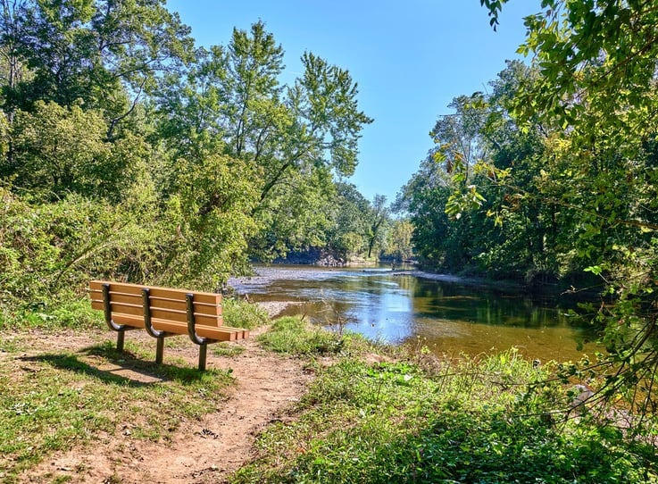 A peaceful, tree-lined river winding through lush greenery, reflecting the natural beauty near senior living near Chalfont, PA — active senior living close to Warrington, PA.