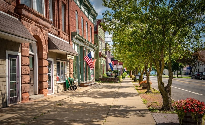 A charming tree-lined street with brick buildings and American flags, capturing the small-town character near assisted living communities near Hatboro, PA serving Bucks County seniors.