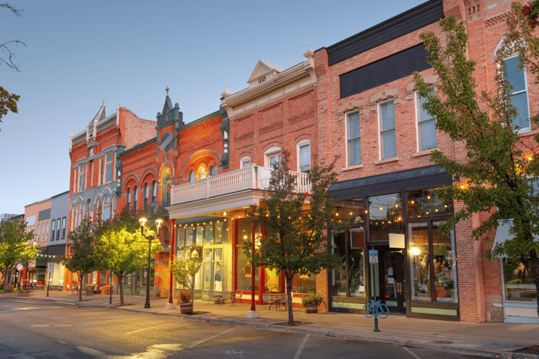 A warmly lit downtown street with historic brick storefronts and trees, showcasing the walkable neighborhoods near The Solana Doylestown — senior living in Doylestown, PA, Bucks County's historic center.