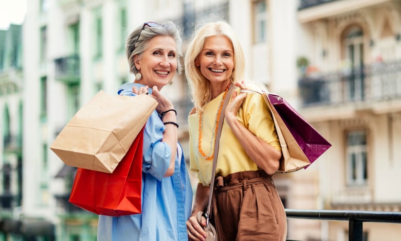 Two people carrying shopping bags and smiling in Eatontown, a nearby destination for shopping and healthcare access close to Arbor Terrace Monmouth.