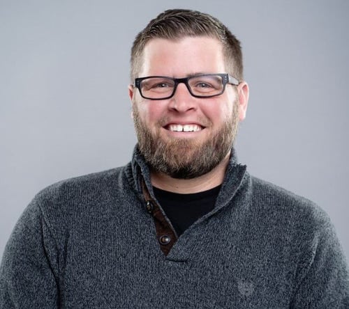 Shawn Feeley, Maintenance Director, smiles in glasses and a gray knit pullover against a soft gray backdrop, caring for senior apartments in Exton, PA, and senior living near South Coventry, PA.