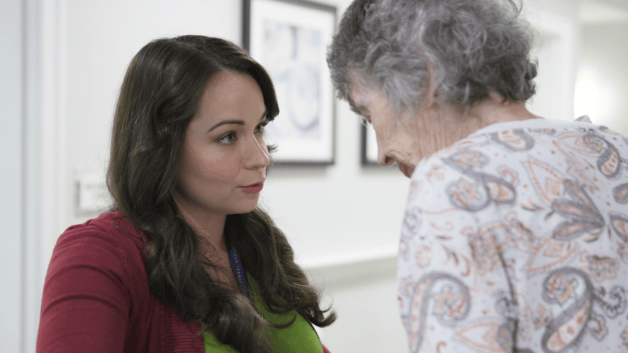 Resident and staff member looking at each other chatting 