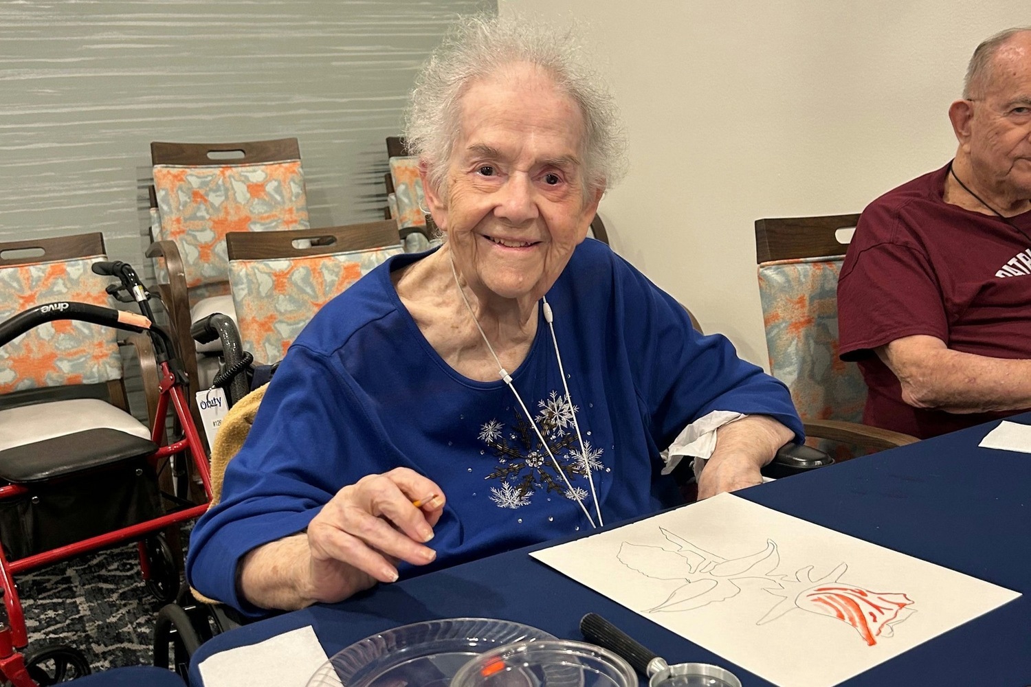 A resident smiles warmly while working on a painting at an art activity at this assisted living community in Fort Myers, FL.
