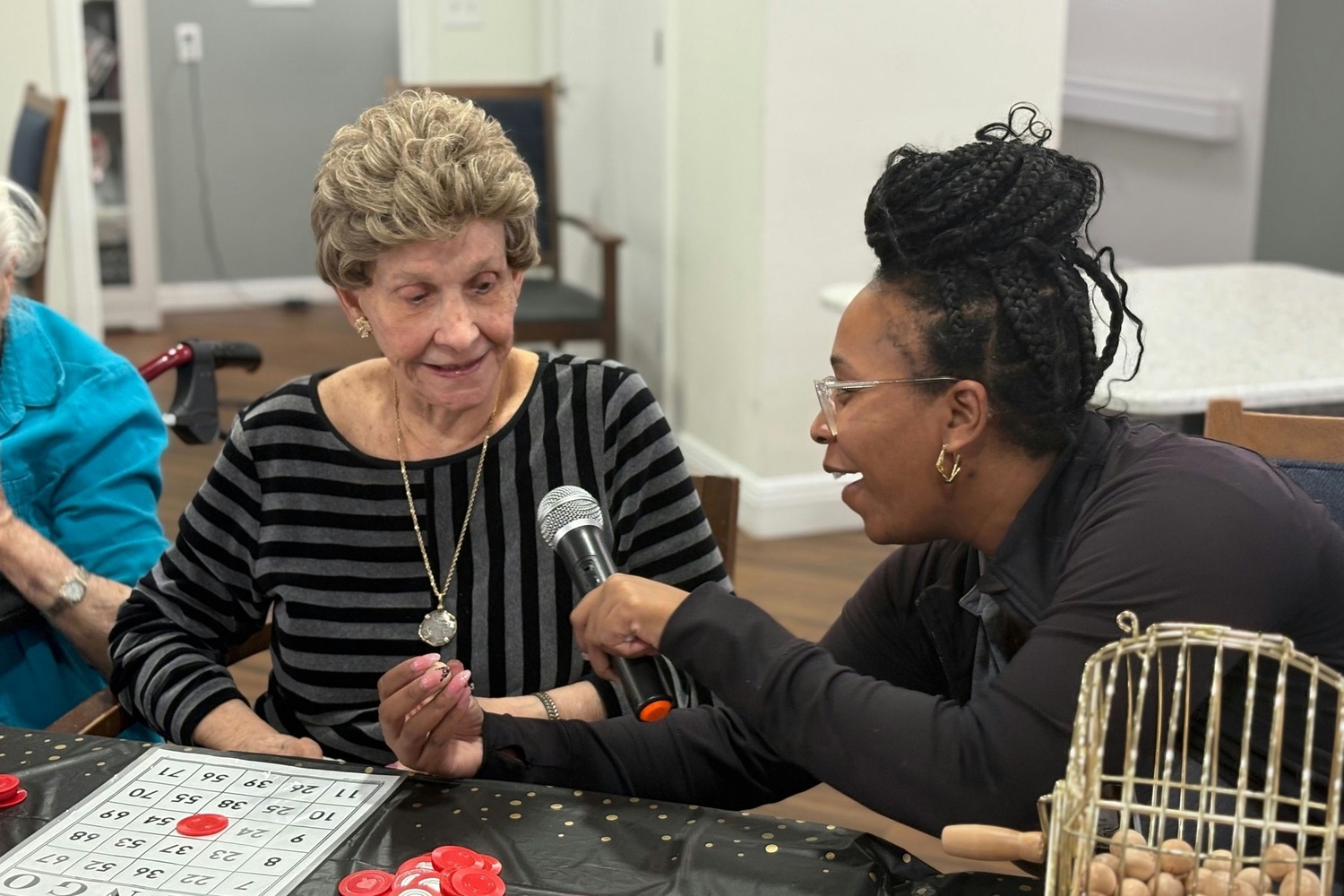 A resident and a staff member share a laugh over a bingo board during a lively activity at Barrington Terrace, a senior living community in Fort Myers, FL, highlighting the warm connections formed every day.