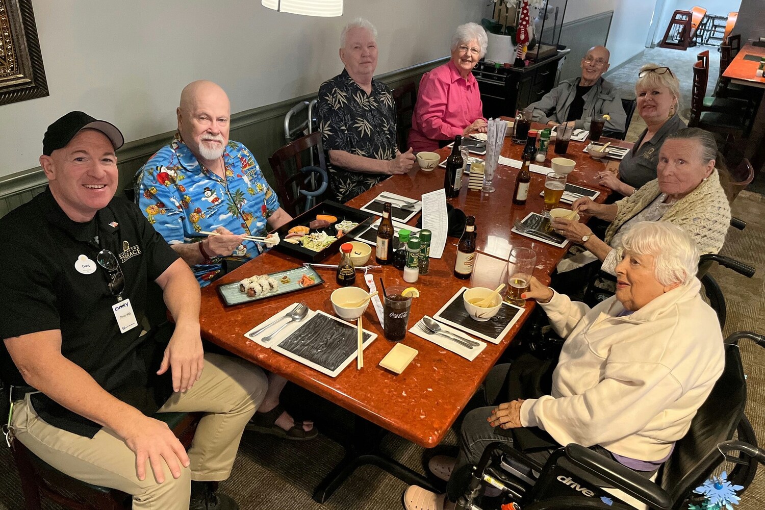 A group of residents enjoying a meal together at a restaurant, sharing food, drinks, and laughter as part of the vibrant lifestyle at Barrington Terrace, a senior living community in Fort Myers, FL.